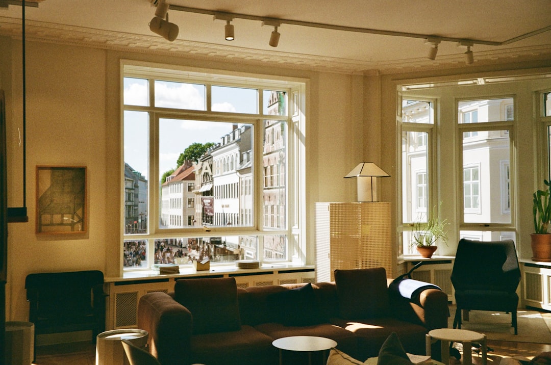 A cozy living room with a stunning city view through large windows, bathed in warm sunlight.