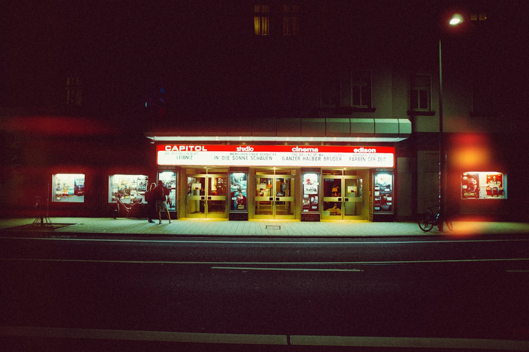 A dimly lit movie theater with a red and white sign, set against a dark street.