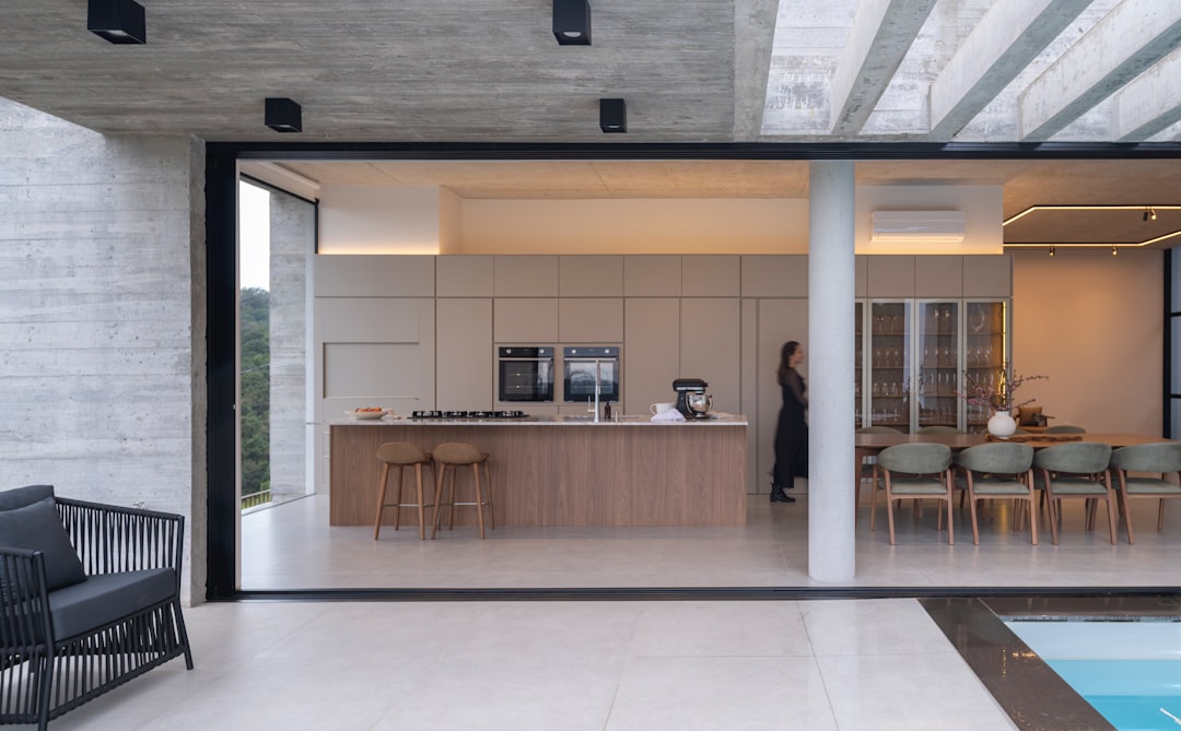 A sleek, modern kitchen with a spacious island and a dining area, seamlessly integrated into a minimalist home.