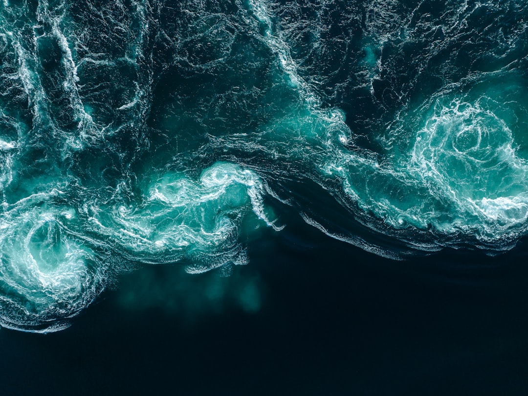 Deep blue ocean waves crash against the shore, creating a mesmerizing display of white foam and turbulent water.