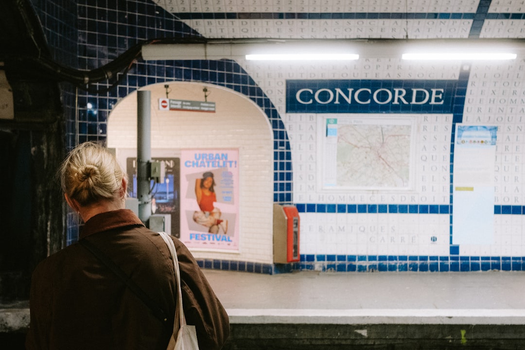 A woman with blonde hair stands in front of a subway station sign, reading "Concorde".