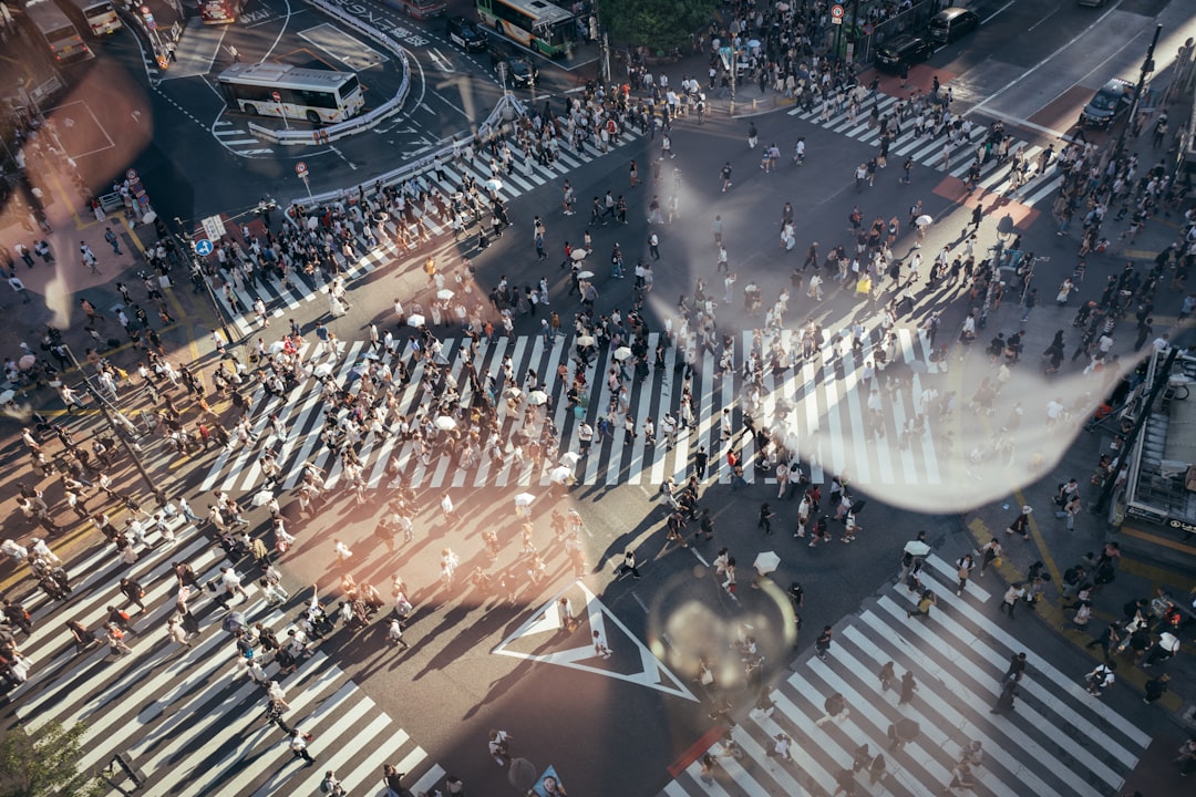 A bustling city street scene with pedestrians crossing the road, captured from above.