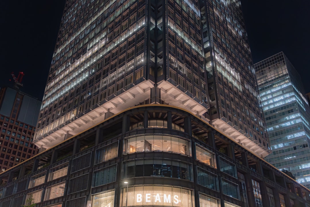 A modern building with a prominent "BEAMS" sign is set against a dark sky, exuding a sleek and contemporary ambiance.