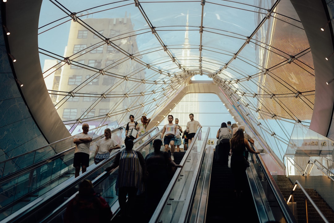 A glass-enclosed atrium with escalators and a cityscape in the background.