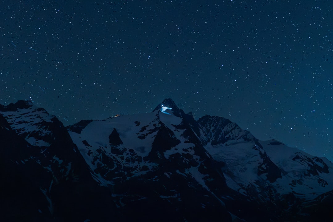 Snow-capped mountains stand tall under a starry night sky.