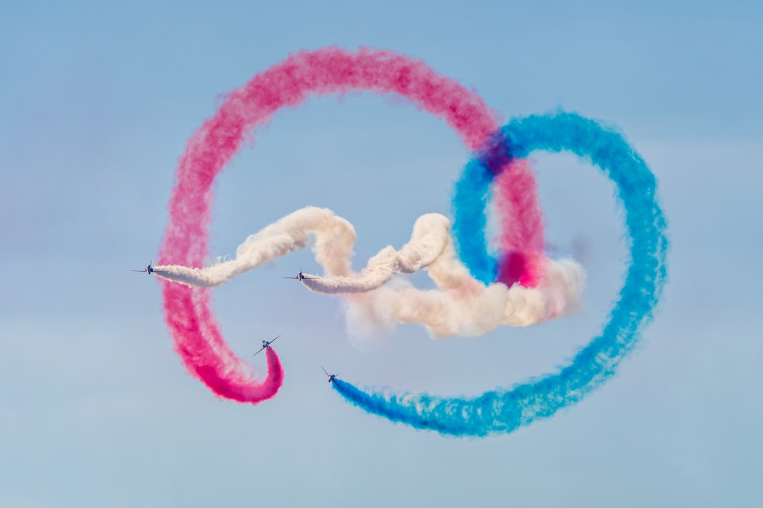 Six planes weave through a vibrant display of red, blue, and white smoke in the sky.