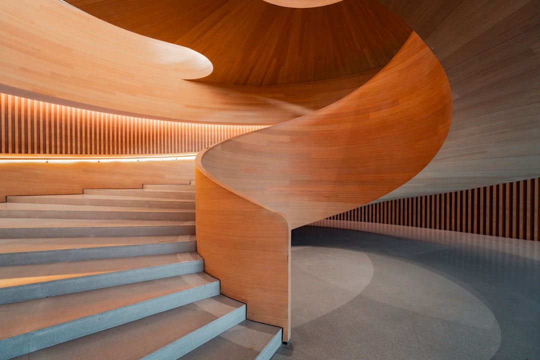 A spiral staircase with a wooden railing winds its way up, set against a backdrop of a wooden wall and ceiling.