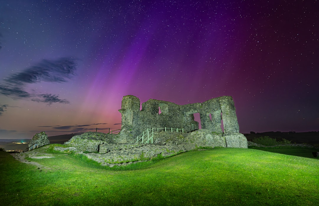 A ruined castle stands on a hill under a starry sky.