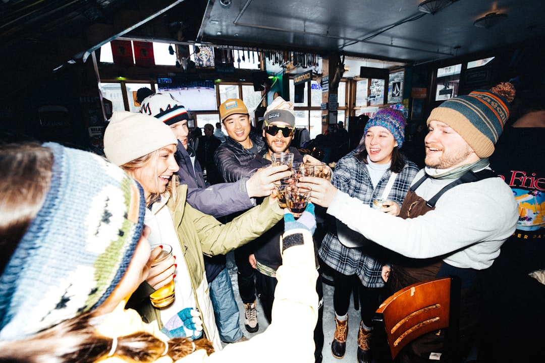 A group of people clad in winter attire raise their glasses in a toast.
