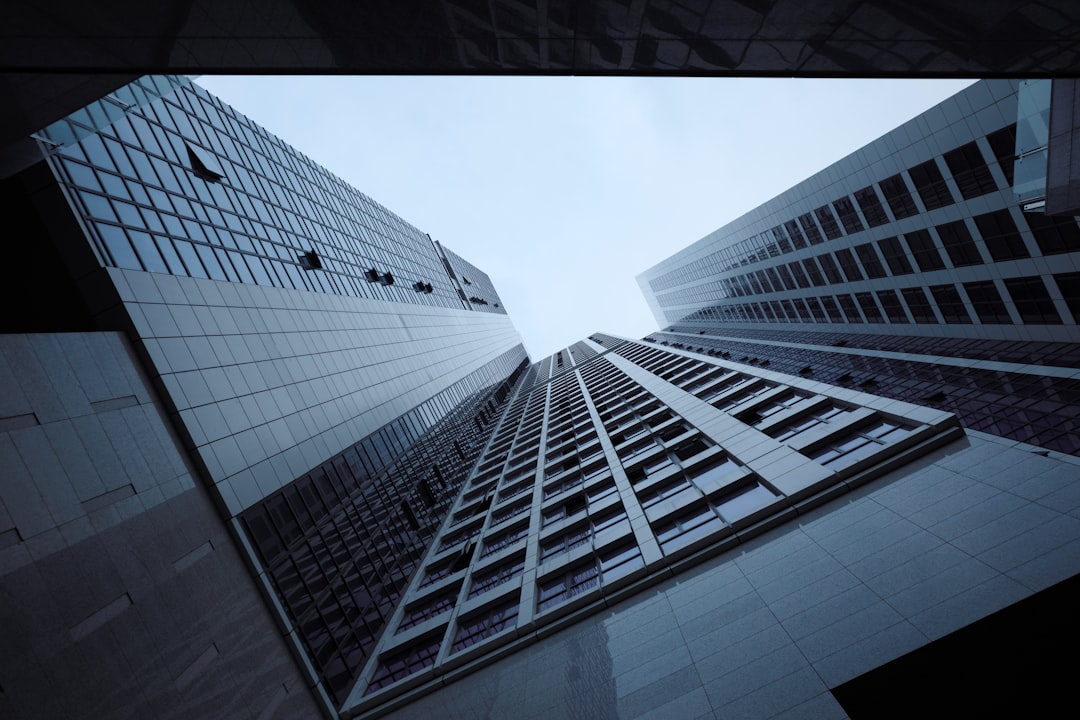 Tall, modern buildings stretch towards a gray sky, their reflective surfaces glinting in the light.