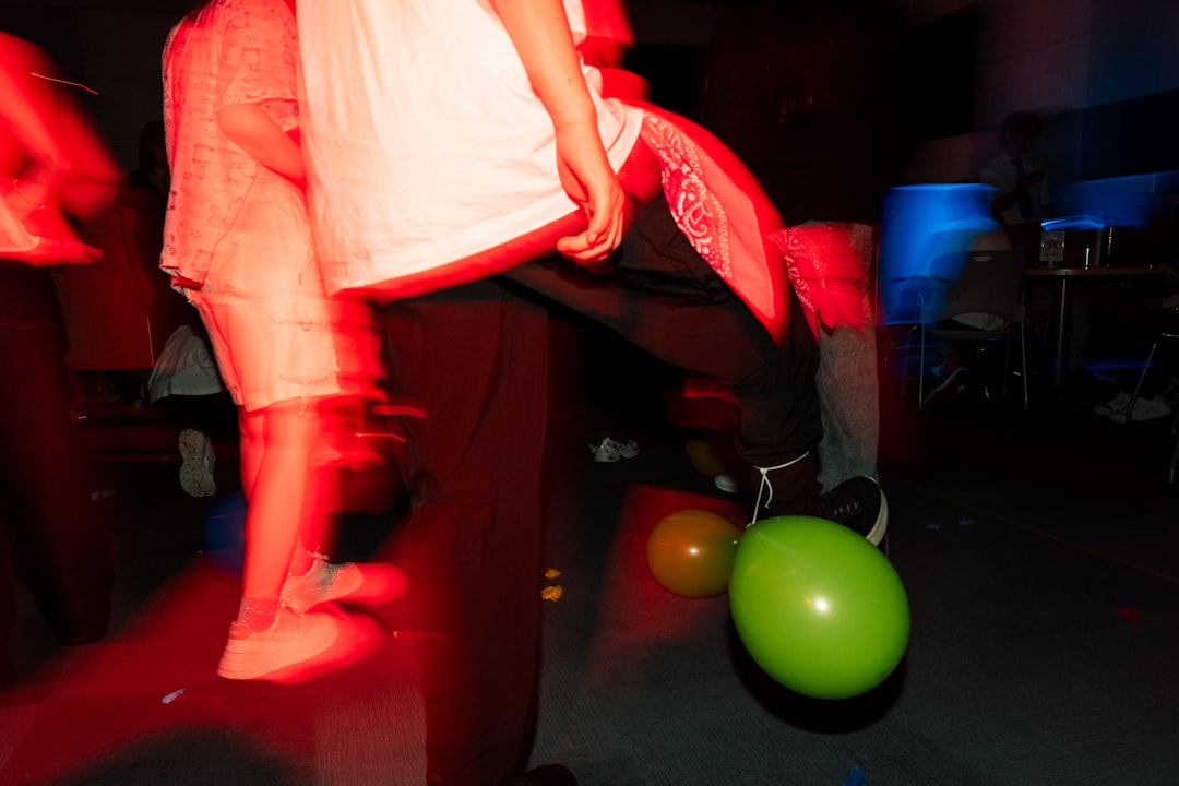 A group of people in a dimly lit room, surrounded by balloons and red light.