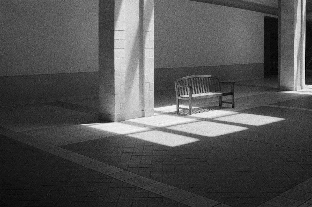 A wooden bench sits in a dimly lit room, illuminated by sunlight streaming through a window.