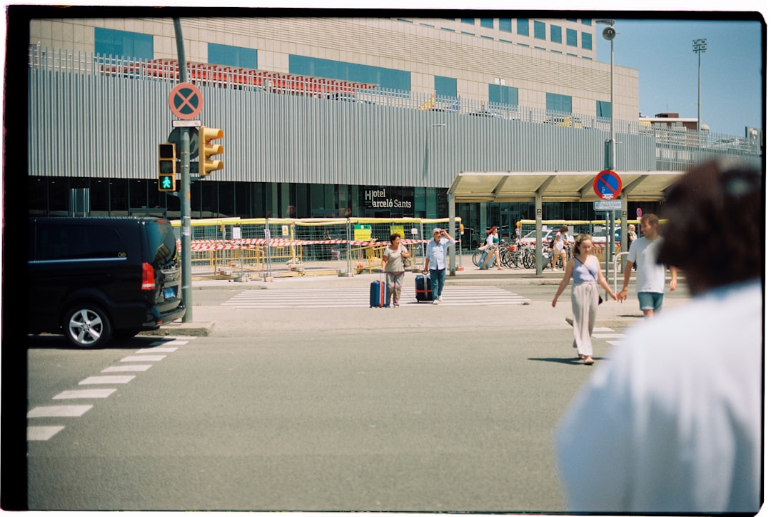 A man in a white shirt stands on the right side of the street, facing away from the camera.