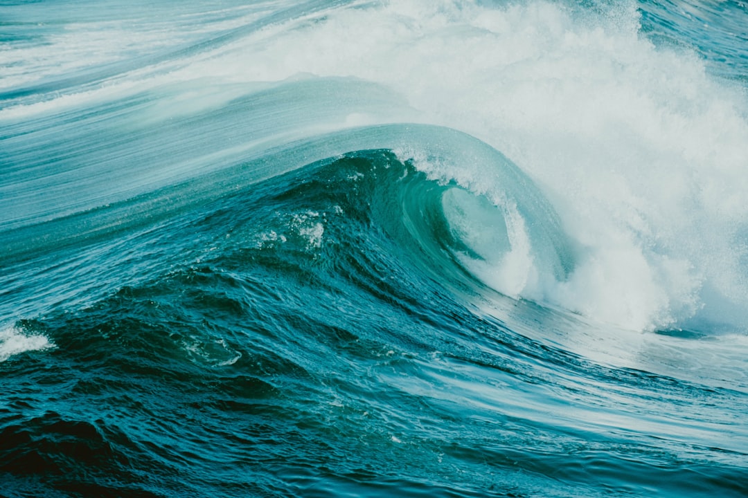 A turquoise wave crashes in a swirling motion.