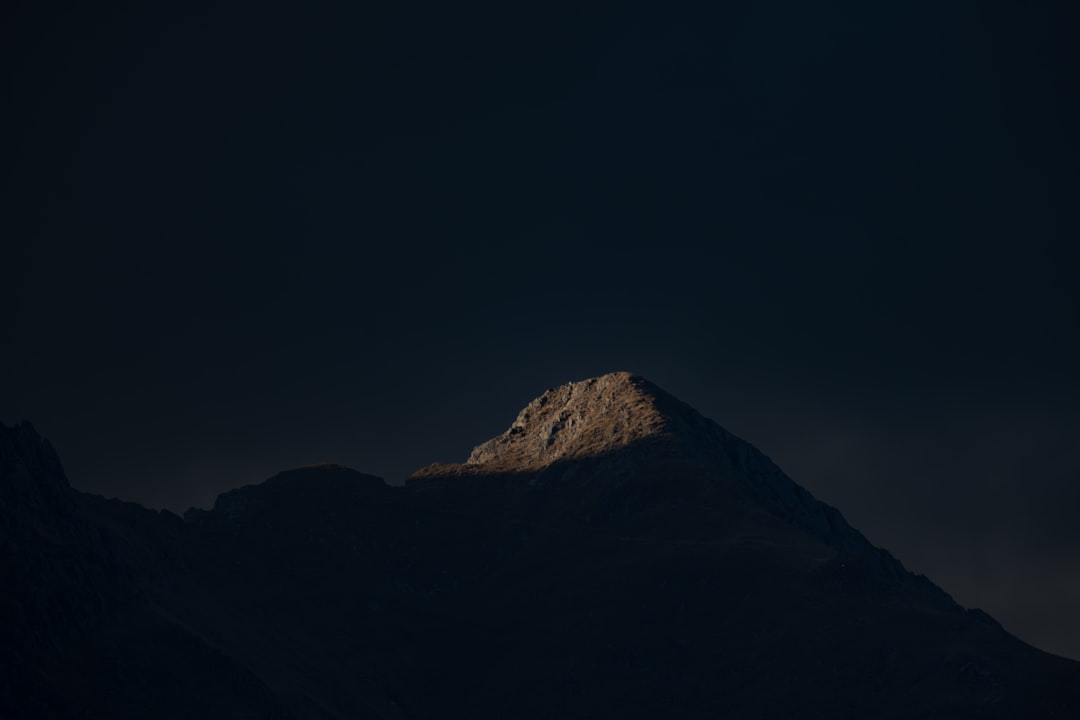 Sunlight illuminates a rugged, rocky peak, casting a warm glow.