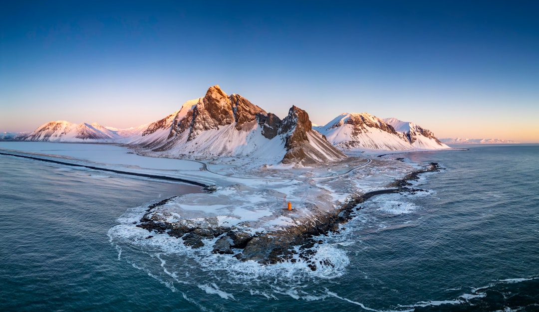 Snow-capped mountains tower over a vast, icy sea.