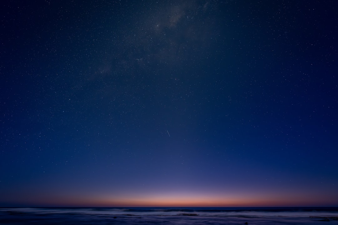 The image depicts a serene beach scene at night, with the ocean waves gently lapping at the shore.