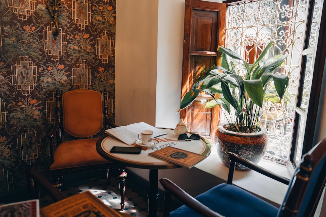 A cozy corner with a table, chair, and potted plant by the window.