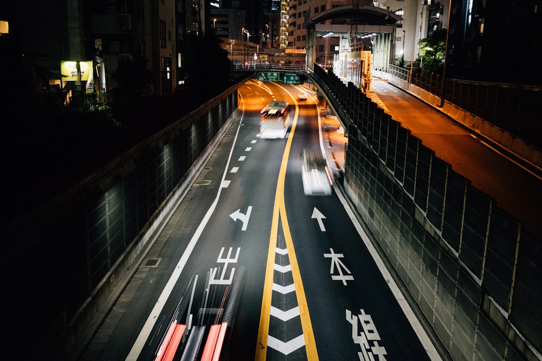 Cars speed through a tunnel in a densely populated city, their lights illuminating the dark surroundings.