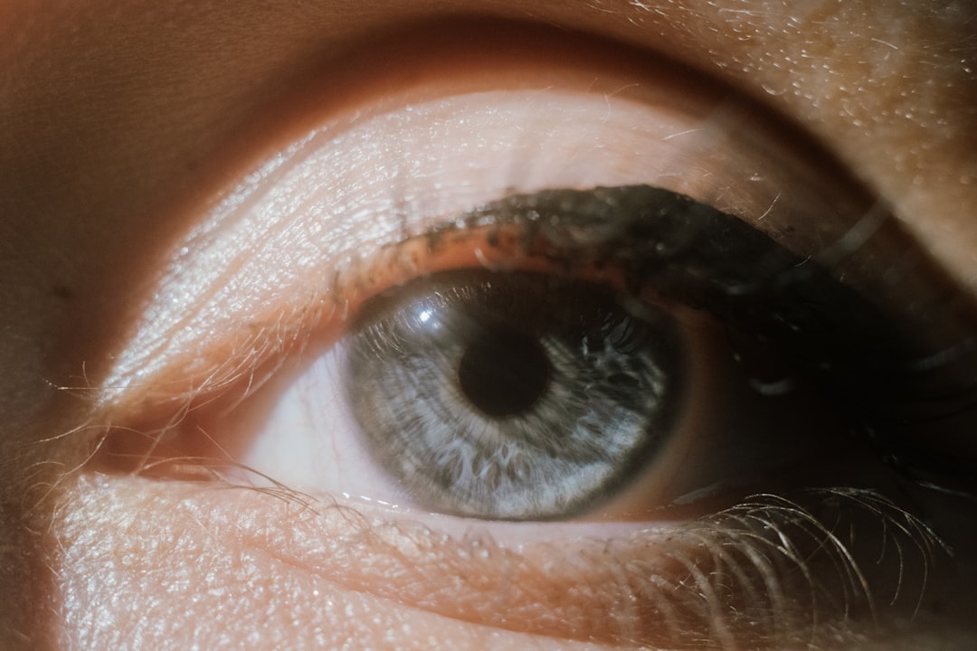 A close-up of a human eye with a striking blue iris and a subtle hint of orange around the edges.