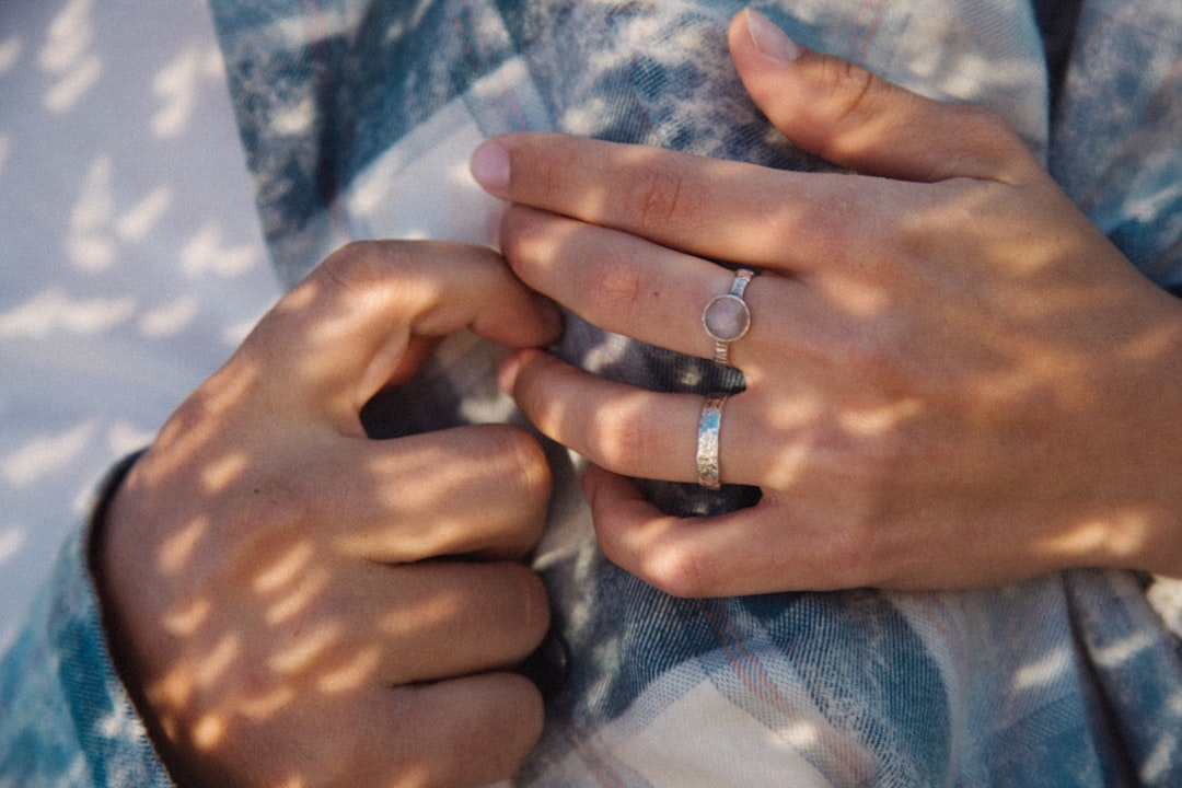 A woman's hands, adorned with rings, gently cradle a soft, patterned fabric.