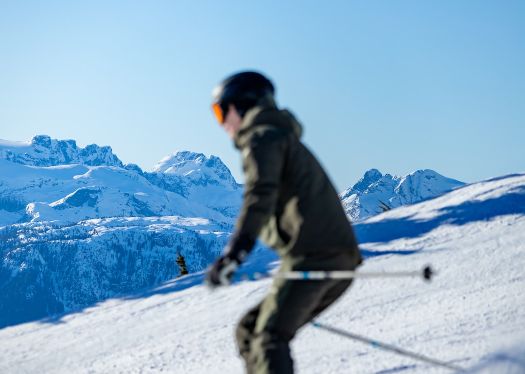 A skier navigates a snowy slope, set against a backdrop of rugged mountains.