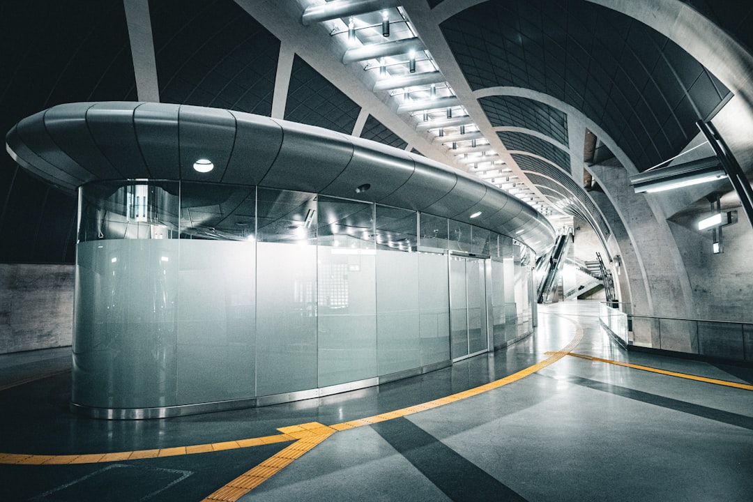 A sleek, modern subway station with a curved ceiling and a glass wall.