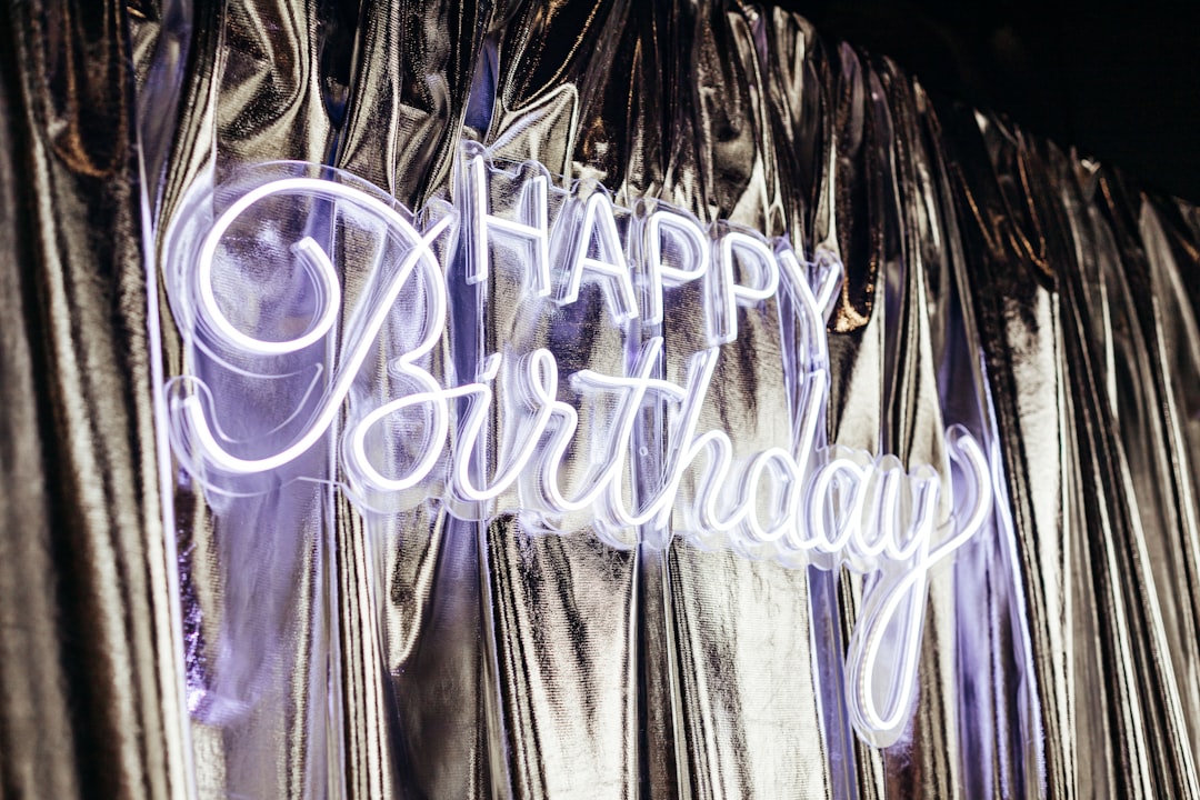 Silver curtains adorned with a neon "HAPPY Birthday" sign.