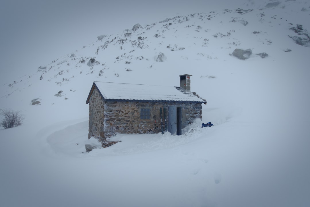 Snow-covered stone cabin nestled in a snowy landscape.