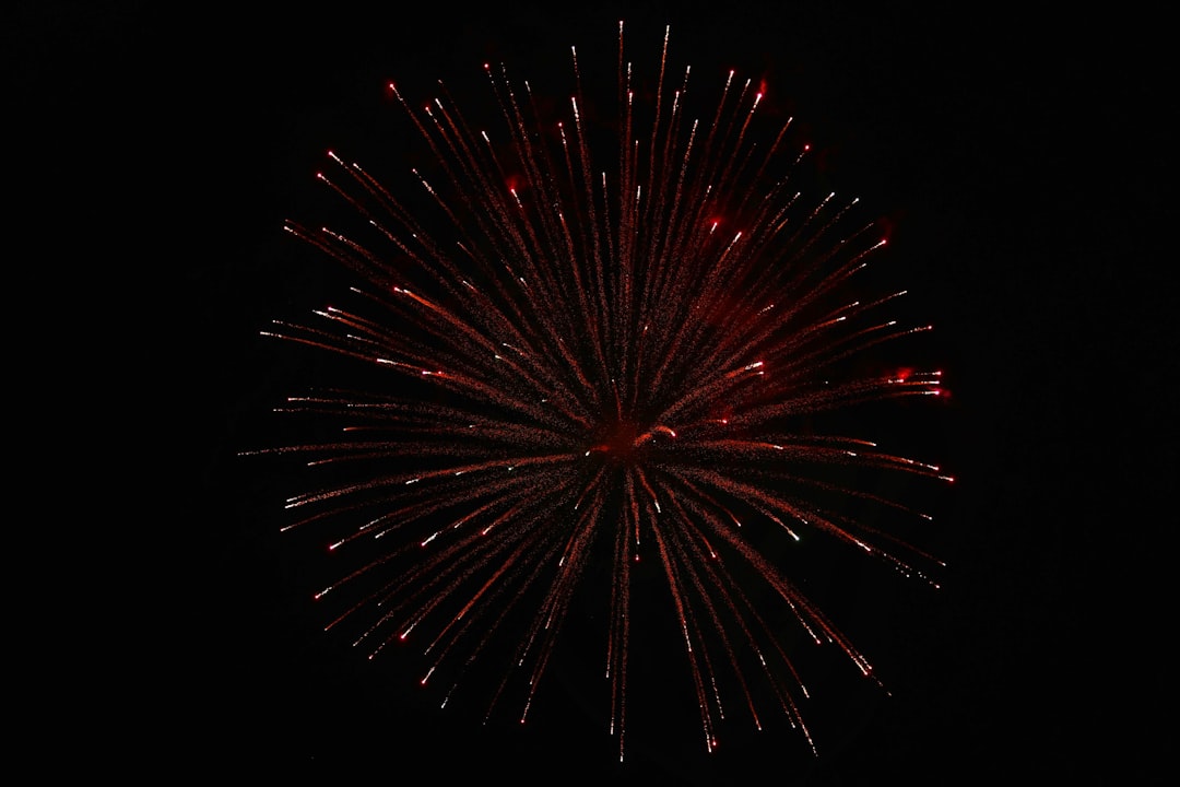 A burst of red sparks explodes in the dark sky.