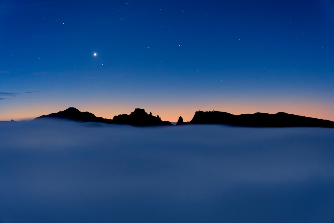Venus shines brightly above a mountain range, silhouetted against a starry sky.