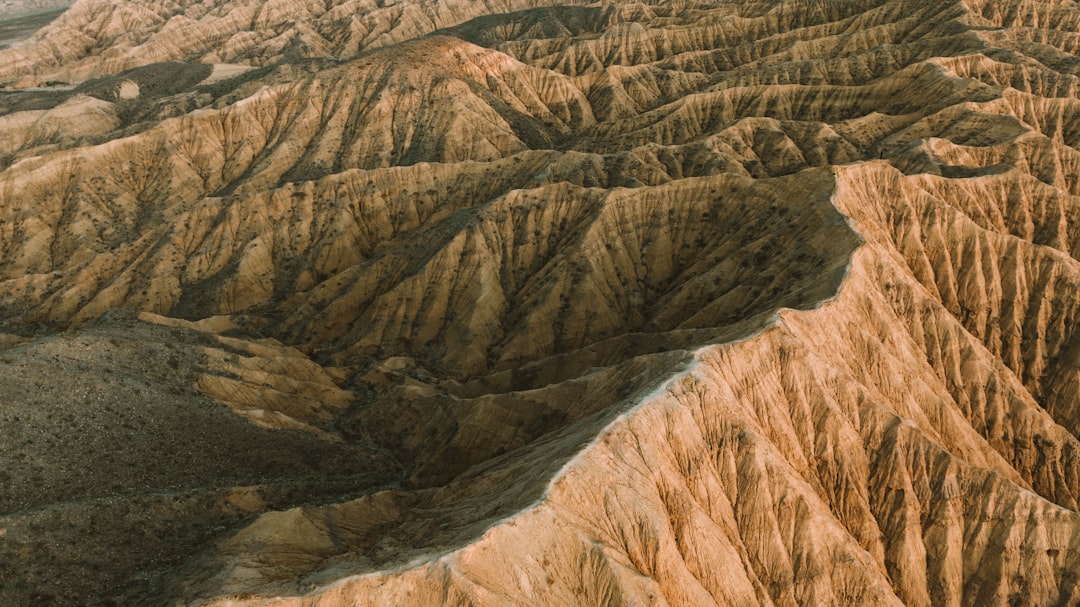 Rugged terrain stretches across the frame, featuring a vast expanse of tan-colored mountains.