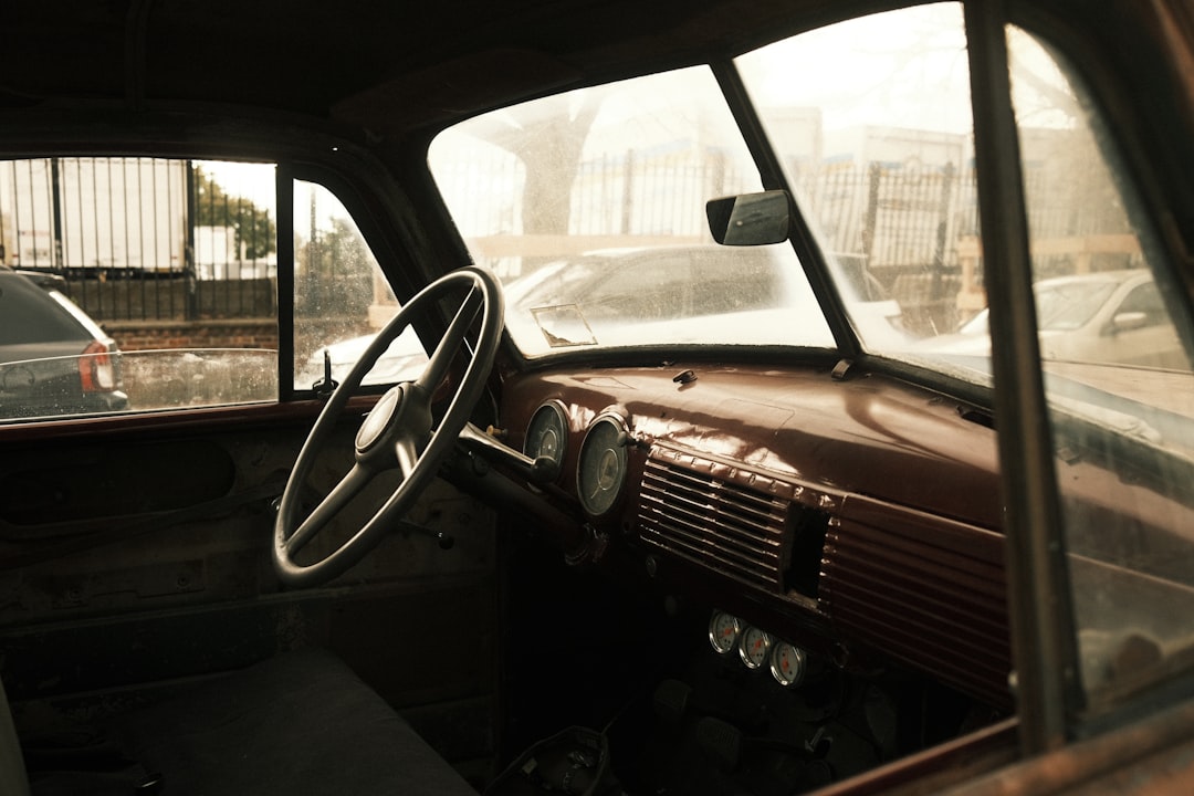 A vintage car's interior is revealed through a window, showcasing a rich brown dashboard and steering wheel.